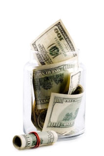A glass jar filled with money sitting on top of a table