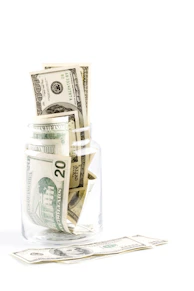 A glass jar getting filled with money. 