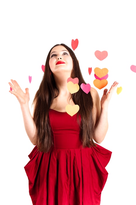 A woman in a red dress with hearts flying around her