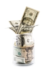 A glass jar filled with money sitting on top of a table