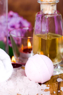 A bottle of oil, a soap ball, and a candle on a table