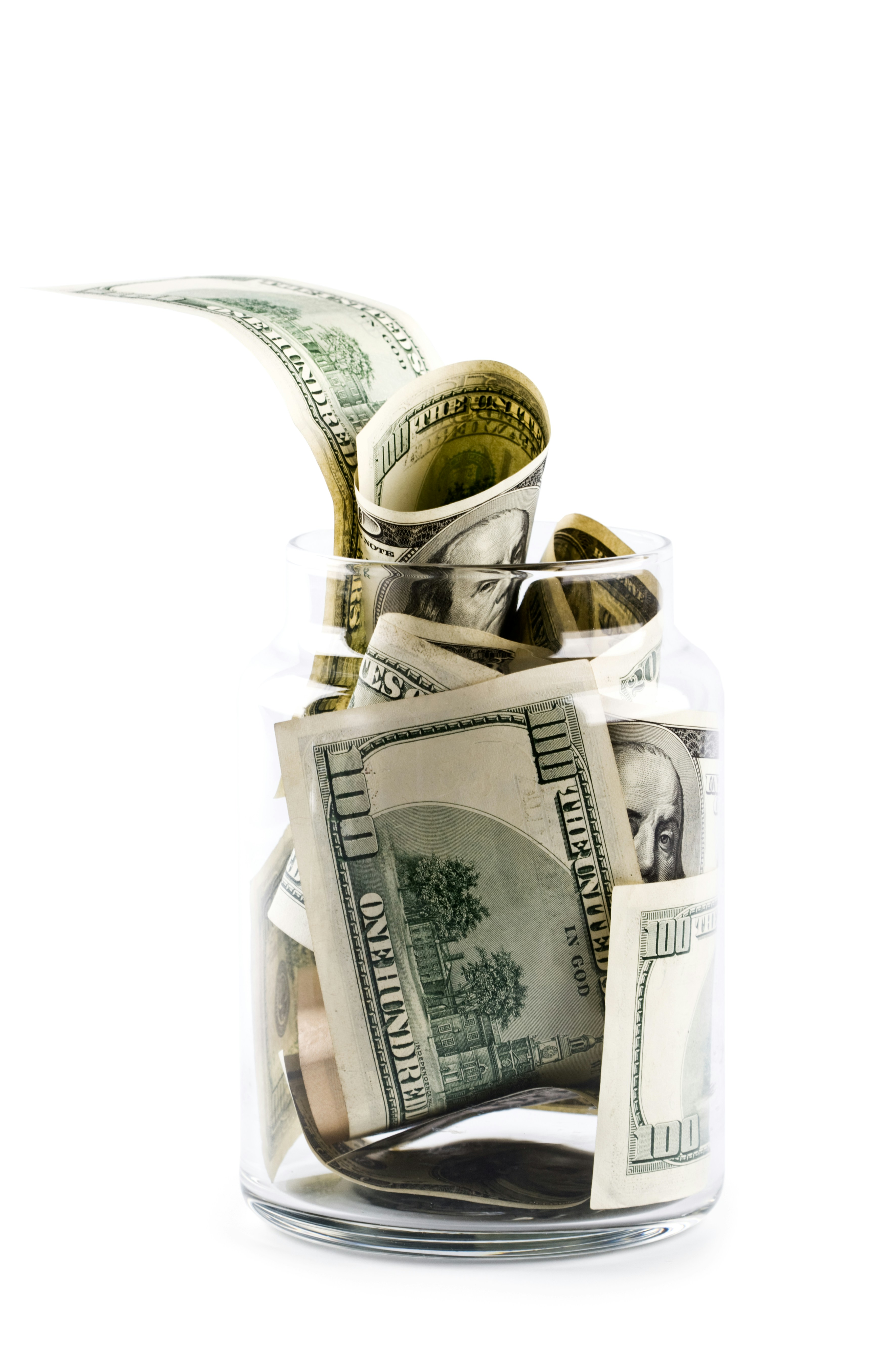 A glass jar filled with money on top of a table
