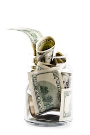 A glass jar filled with money on top of a table