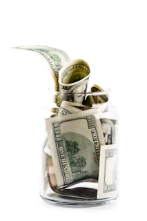 A glass jar filled with money on top of a table