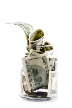 A glass jar filled with money on top of a table