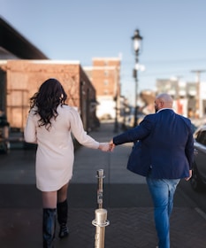 A man and woman walking down a street holding hands