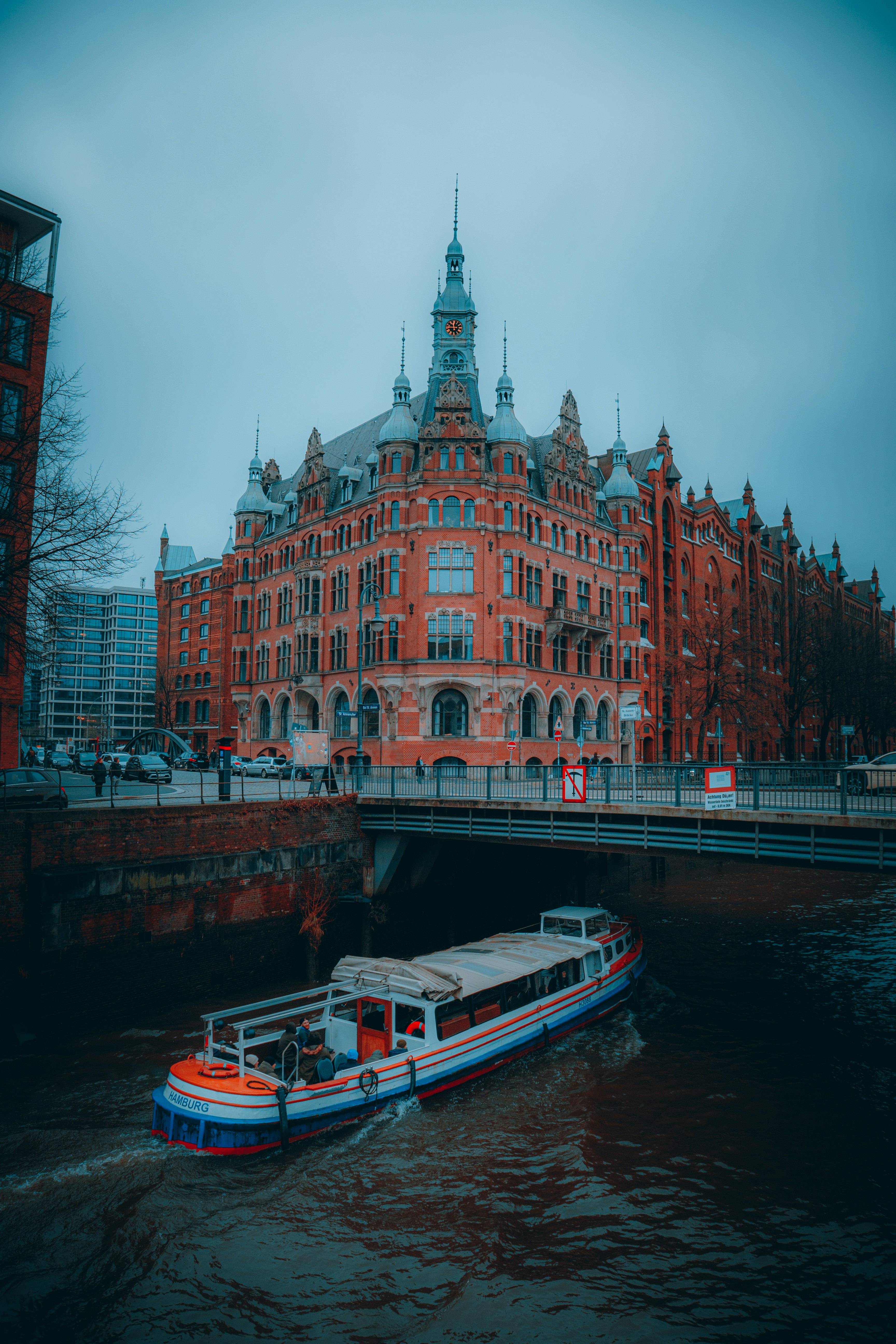 A boat traveling down a river next to a tall building