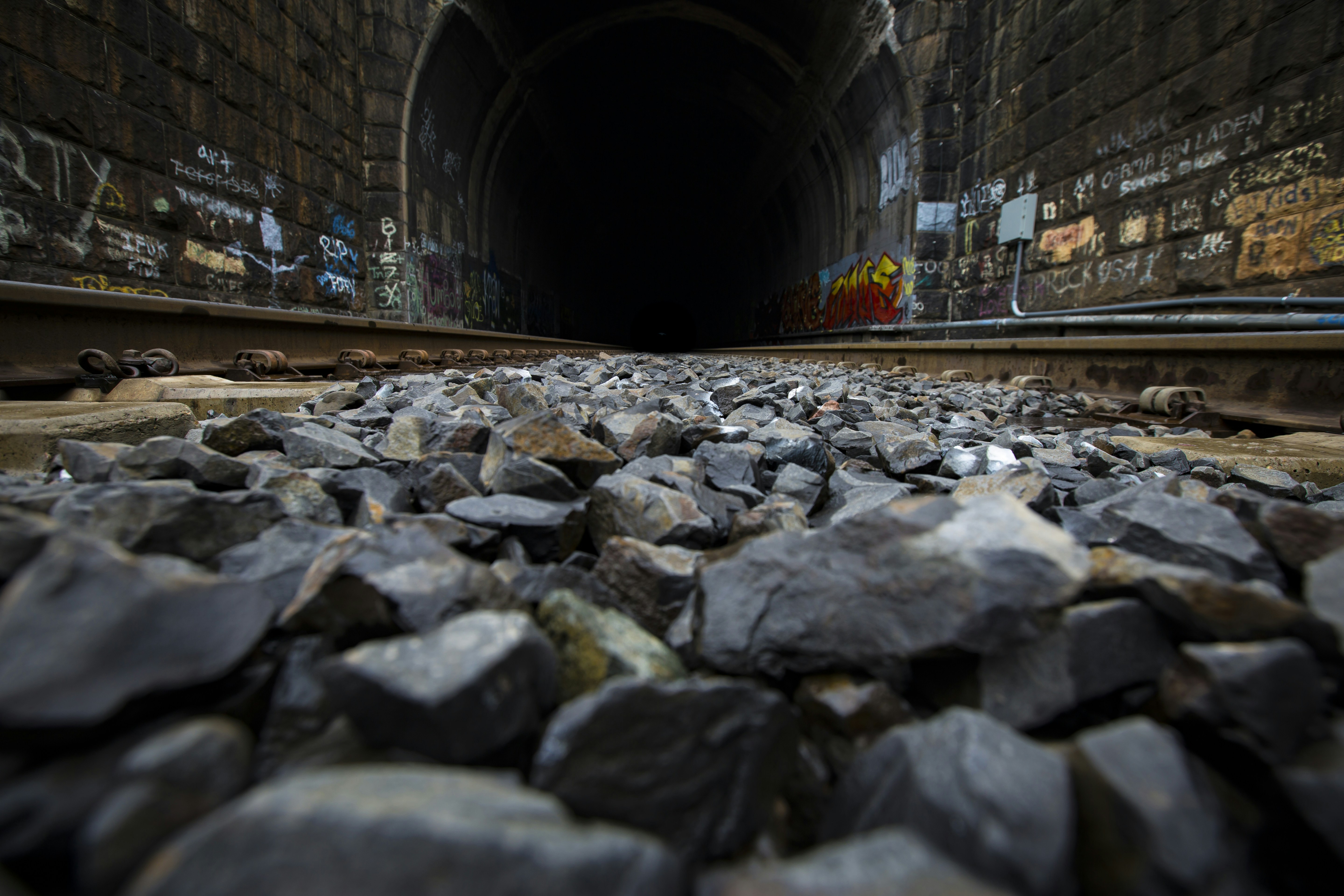 A dark tunnel with rocks and graffiti on the walls