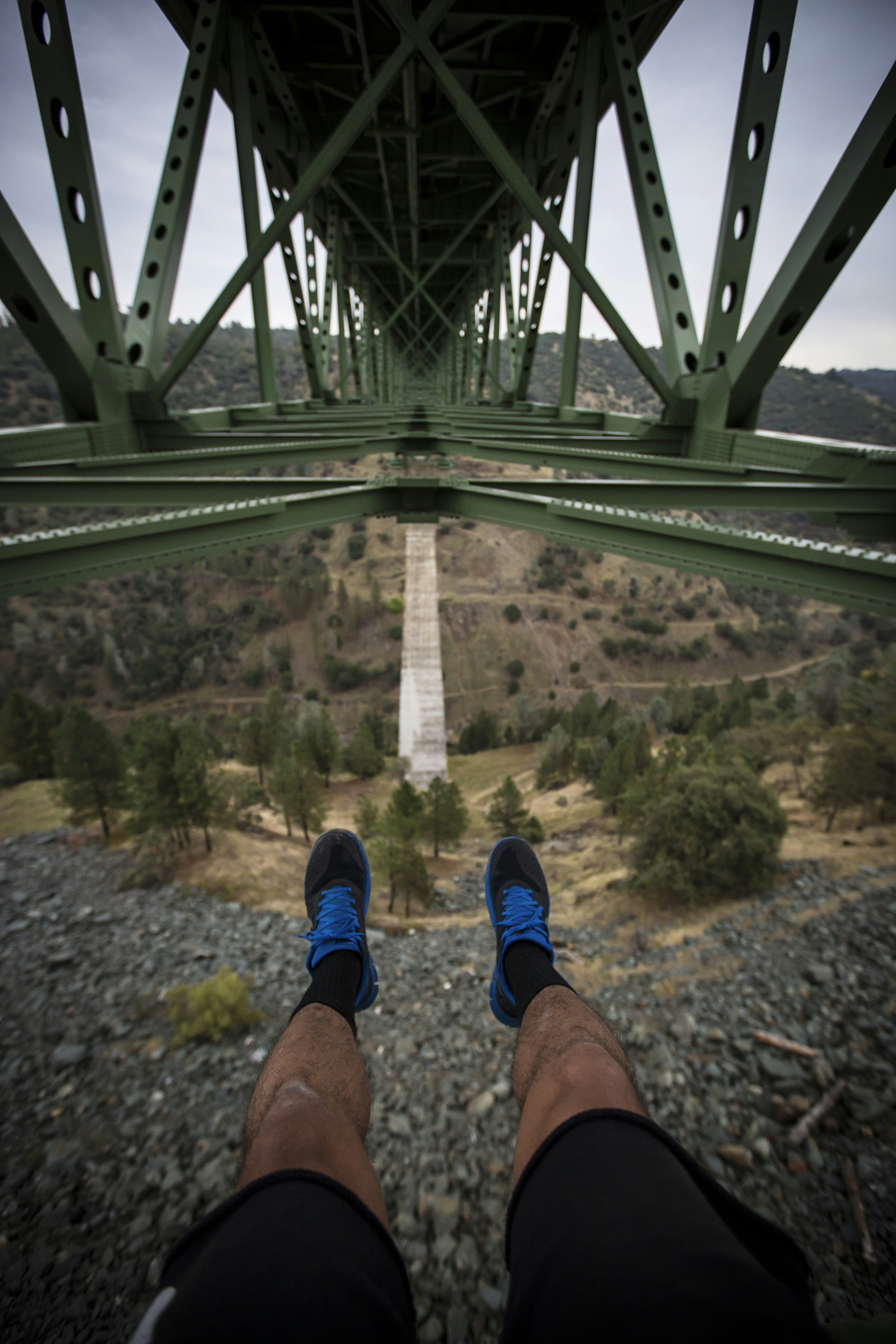 A person standing on a bridge with their feet up