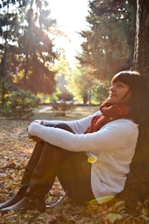 A woman sitting on the ground next to a tree