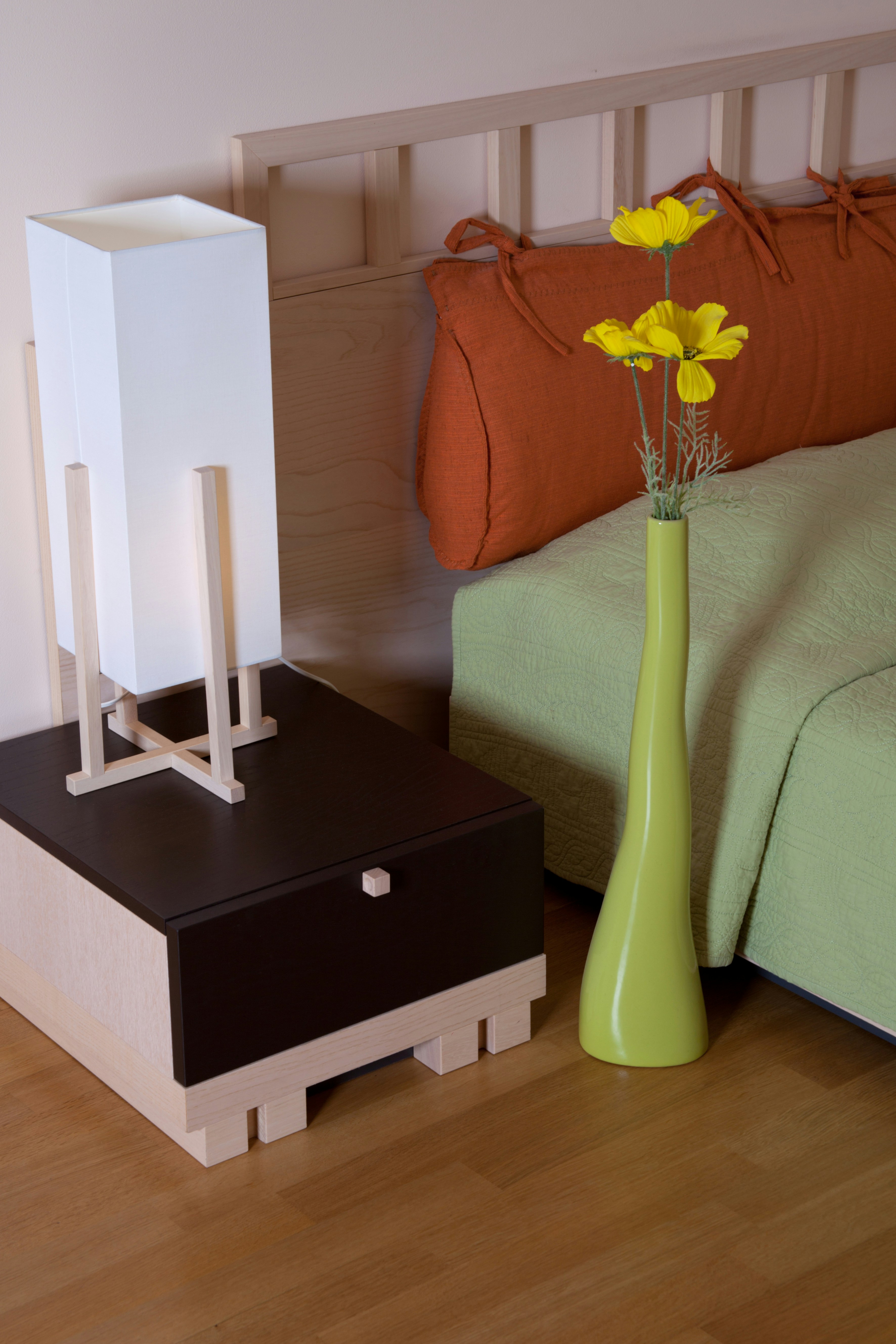A bedroom with a bed and a vase with flowers
