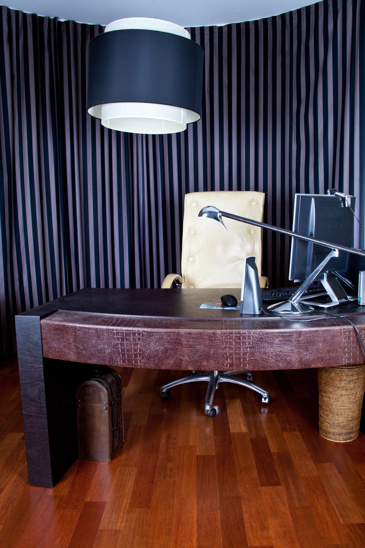 Mahogany side table with brass lamp and leather-bound books.