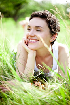 A woman laying in the grass with her hand on her chin