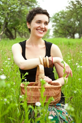 A woman sitting in the grass with a basket