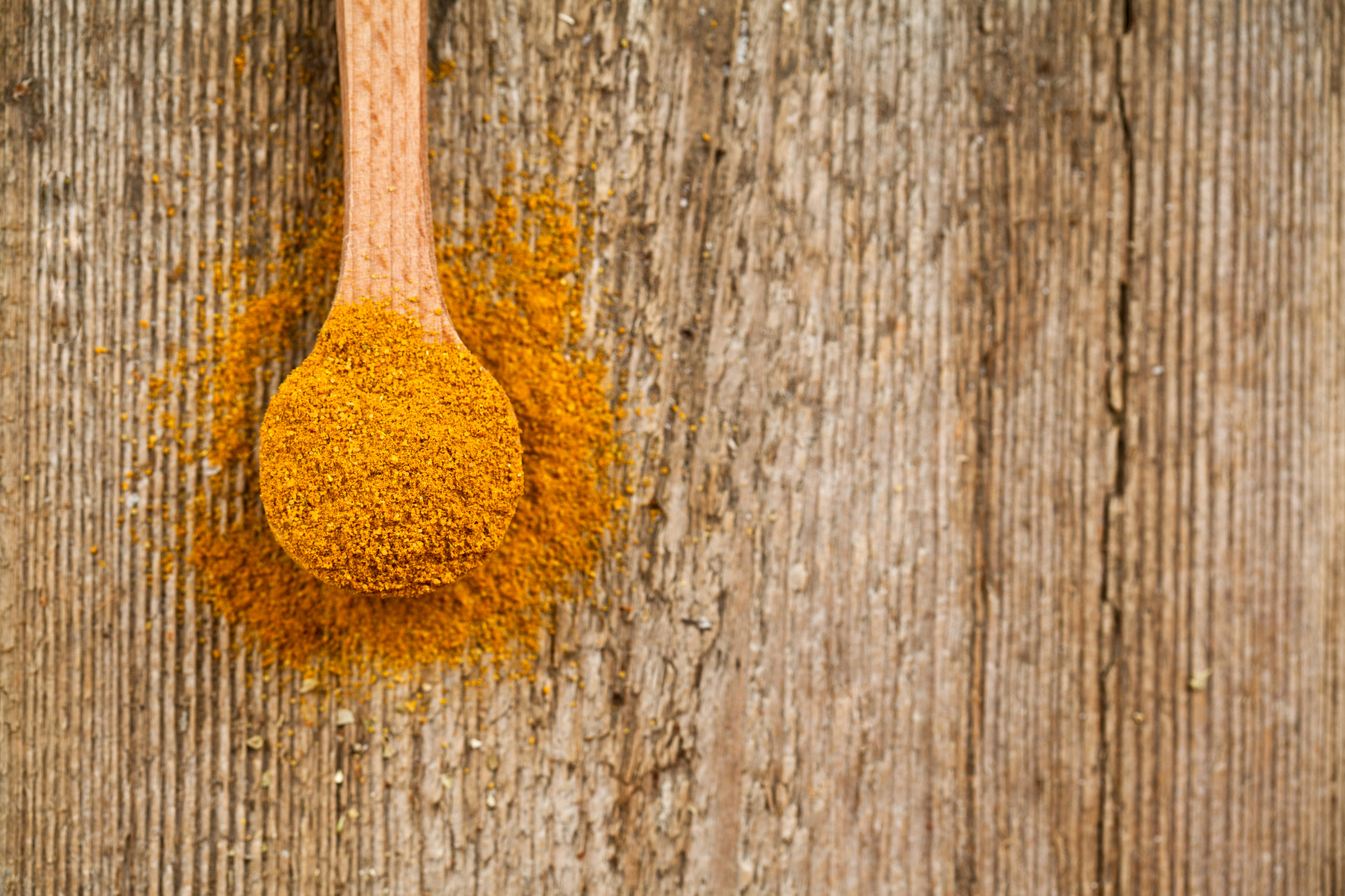 yellow curry powder in wooden spoon - coriander substitute spice