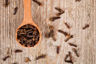 A wooden spoon filled with seeds on top of a wooden table