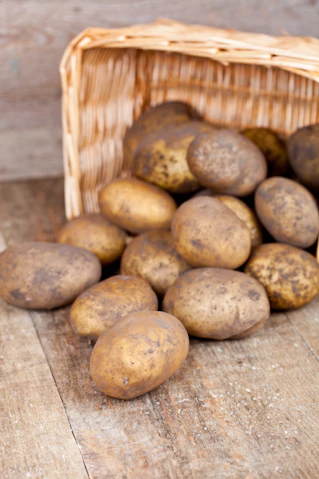 A basket full of potatoes sitting on a wooden table