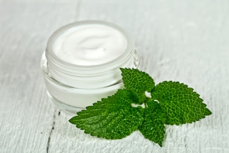 A jar of cream with a green leaf on top of it