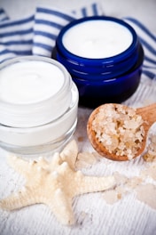 A jar of cream next to a wooden spoon