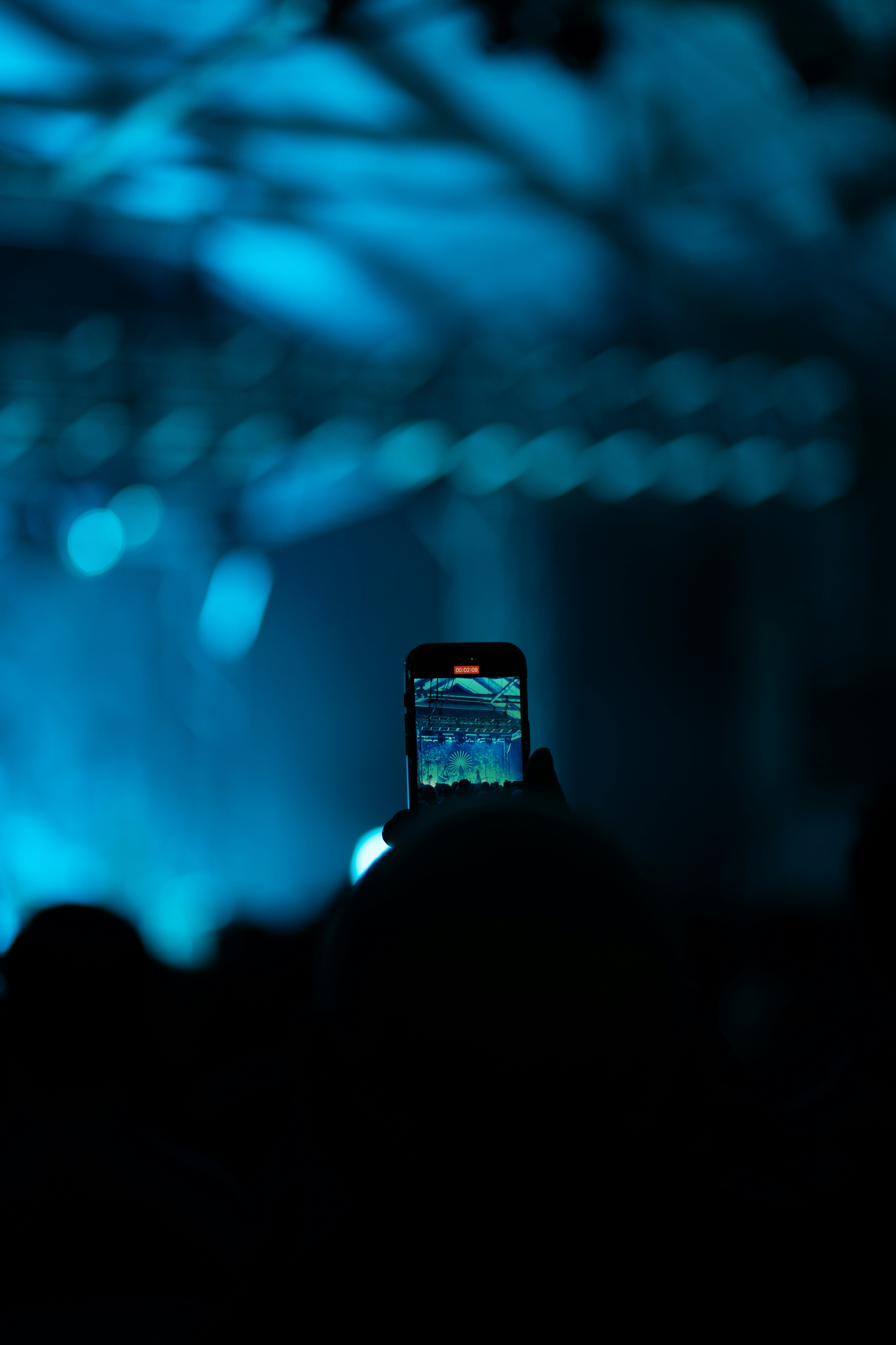 A person taking a picture of a concert with a cell phone