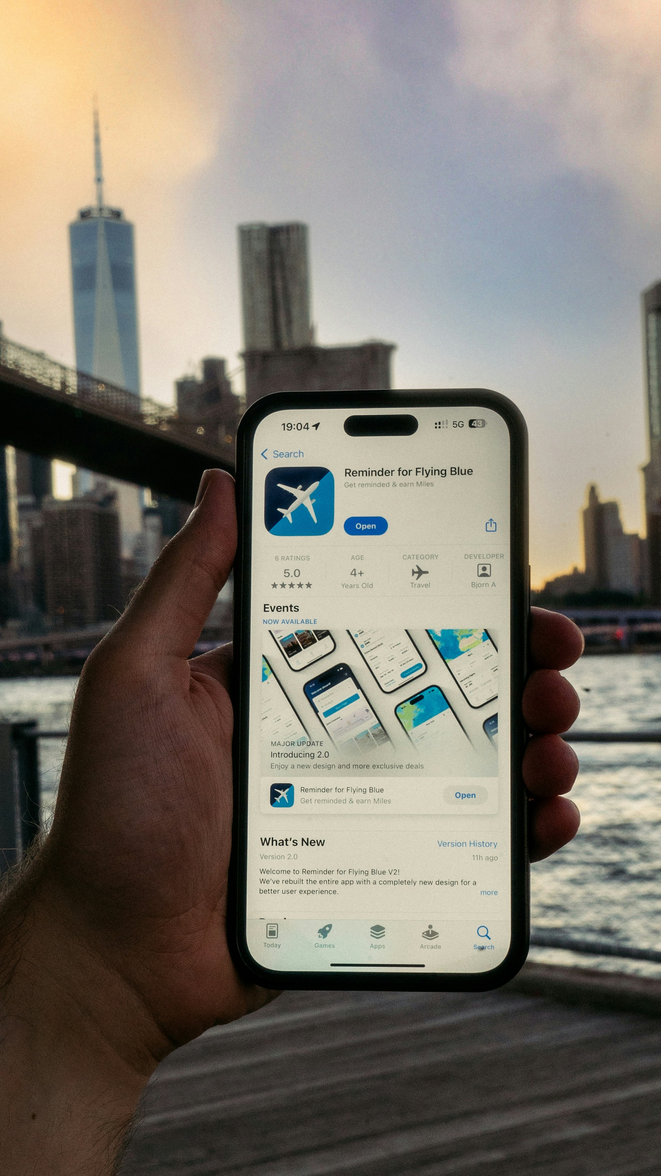A person holding up a cell phone in front of a bridge
