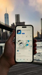 A person holding up a cell phone in front of a bridge