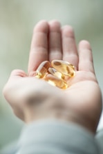 A person holding two pills in their palm