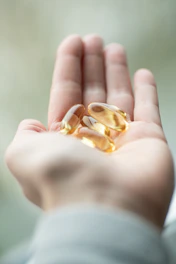 A person holding two pills in their palm