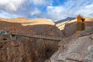 A suspension bridge over a canyon with mountains in the background