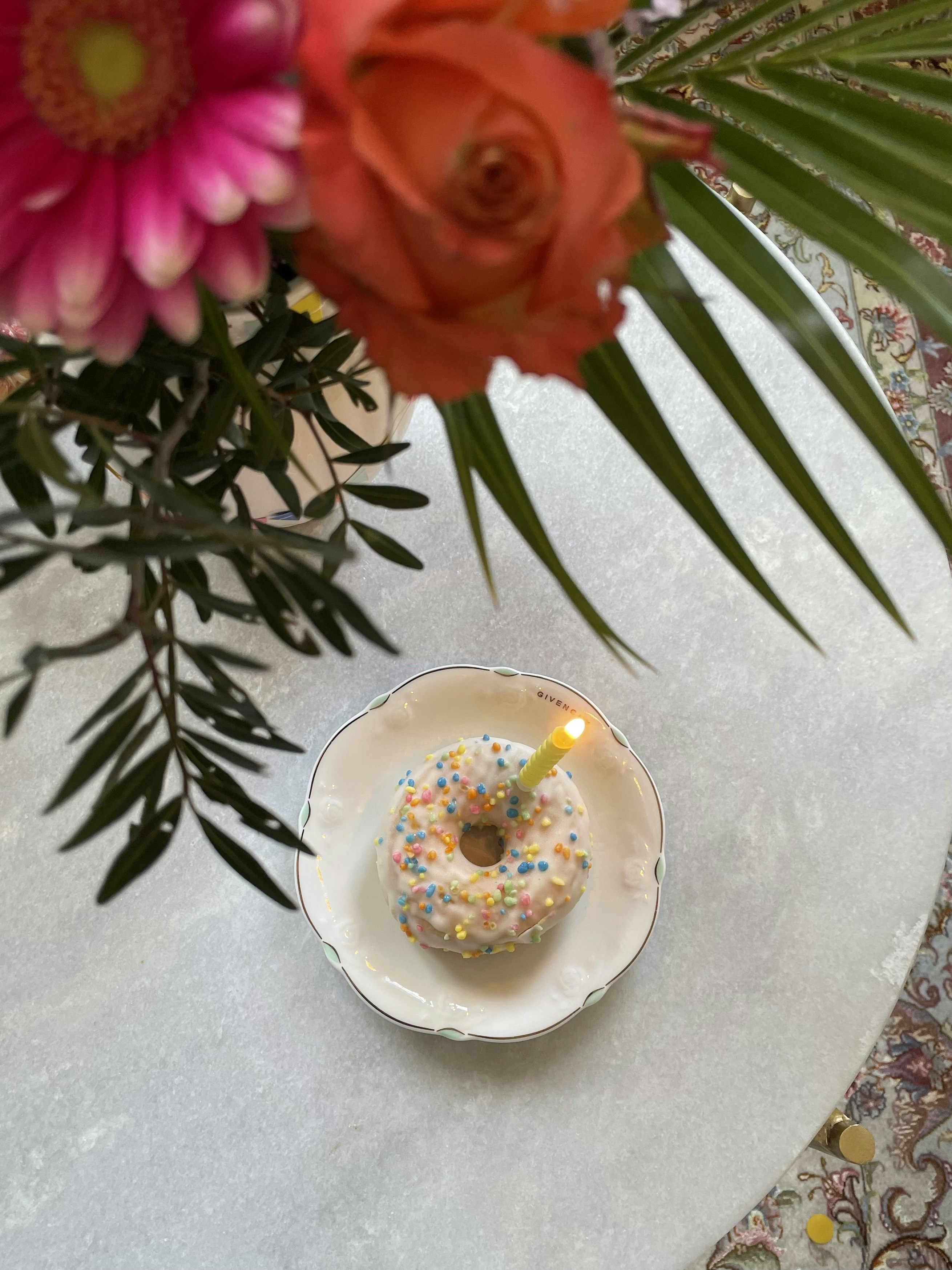 A donut with sprinkles and a candle on a plate
