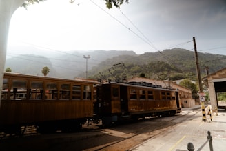 The Soller Train traveling down train tracks next to a mountain