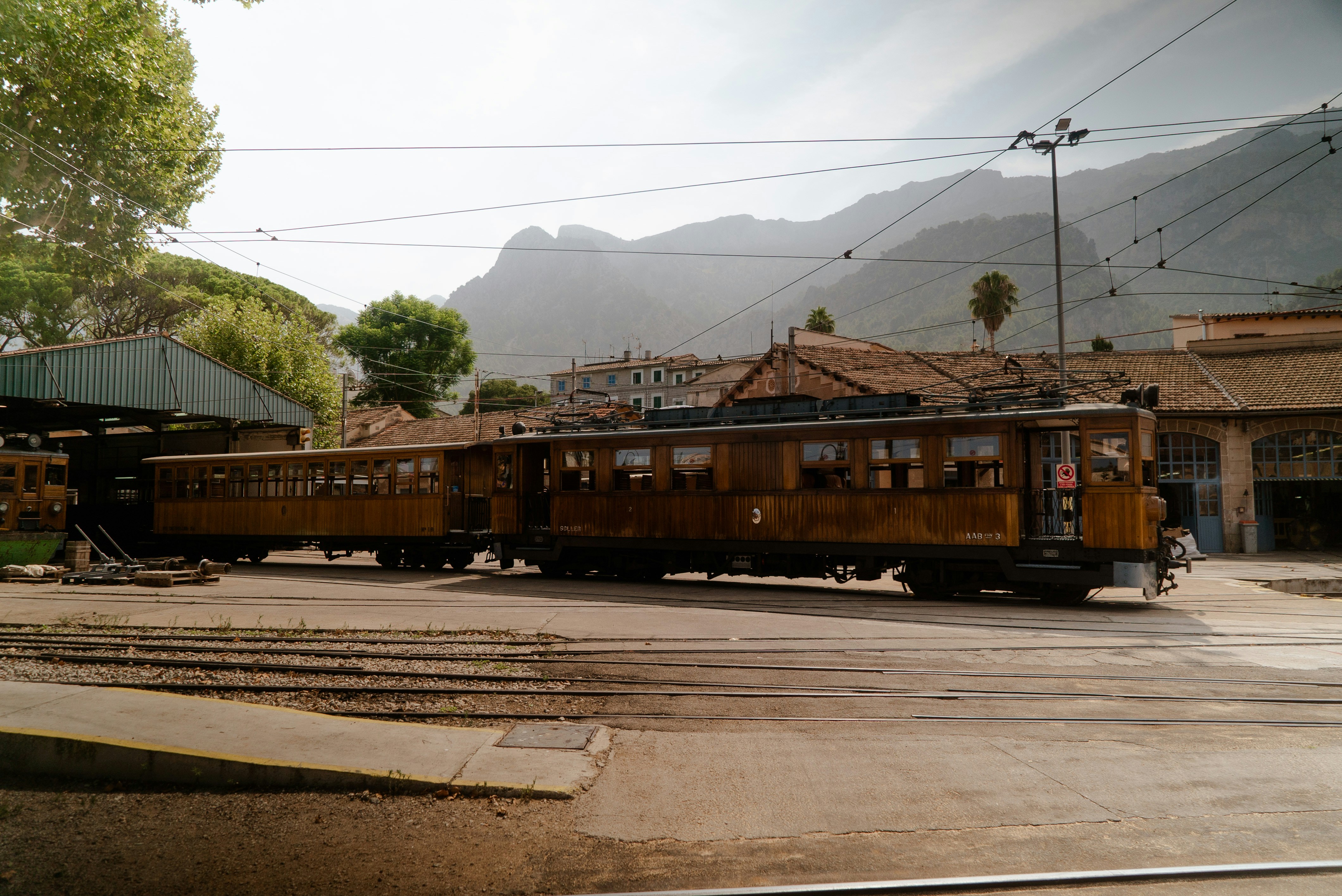 A train traveling past a train station next to a mountain