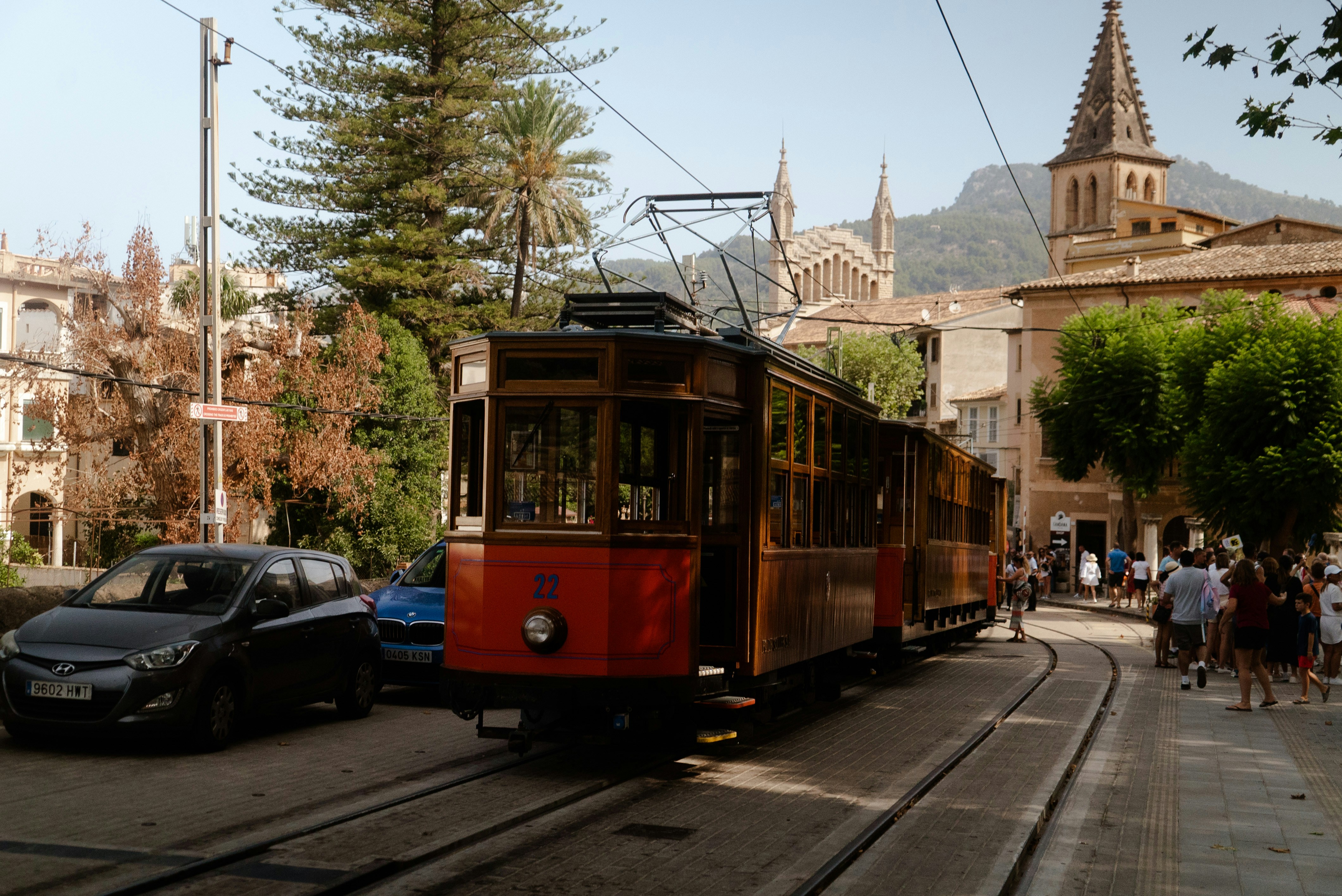 A red trolley car traveling down a street next to tall buildings
