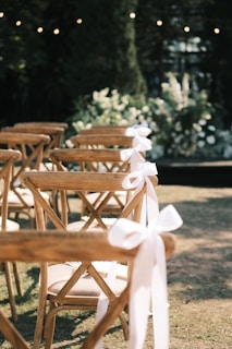 A row of wooden chairs sitting on top of a grass covered field