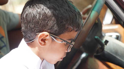 A young boy in a white shirt and tie sitting in a car