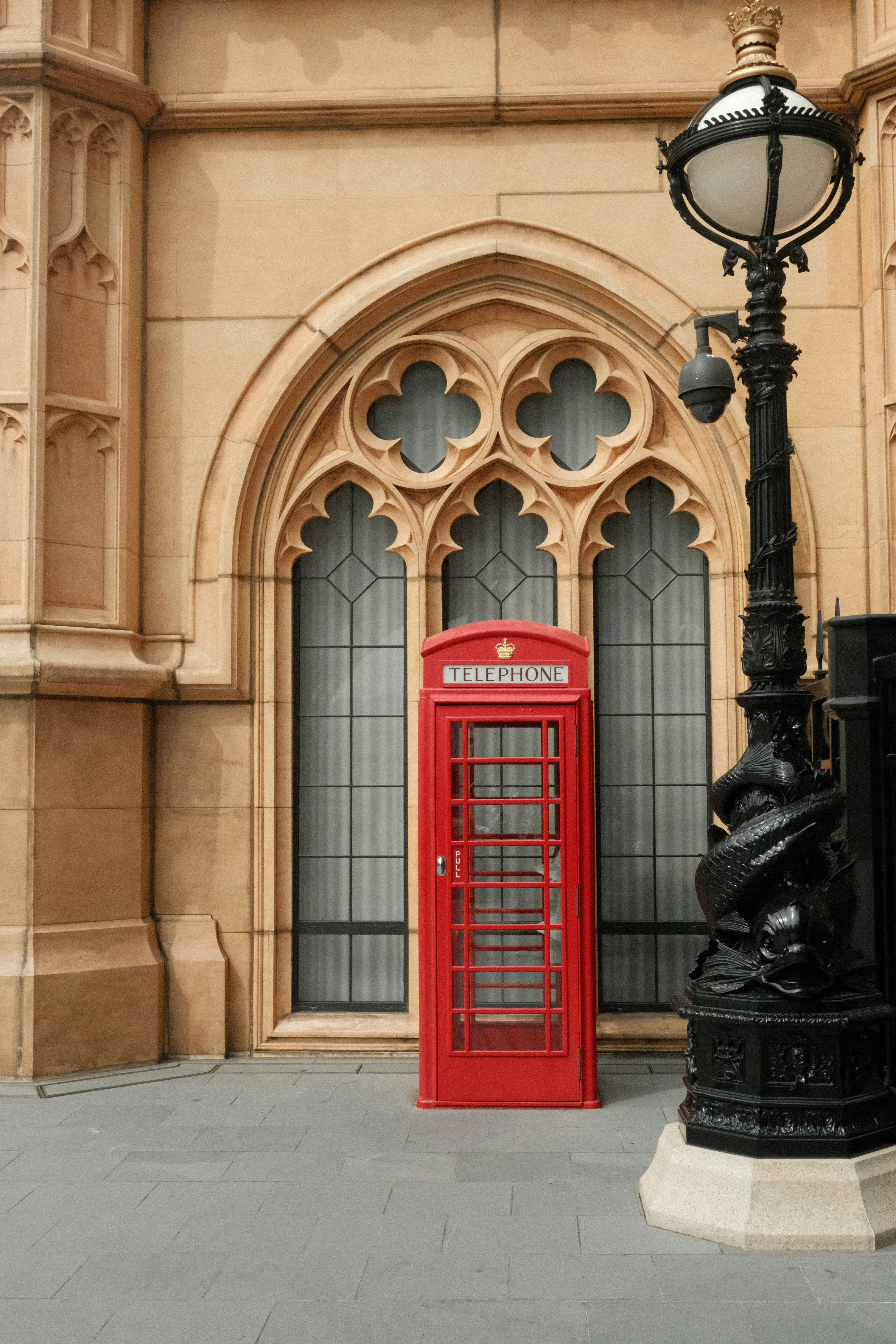 A red phone booth sitting in front of a tall building