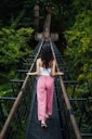A woman walking across a suspension bridge in the jungle