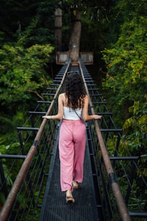 A woman walking across a suspension bridge in the jungle