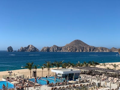 An aerial view of a beach with a pool and mountains in the background
