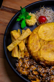 A black plate topped with meat and vegetables