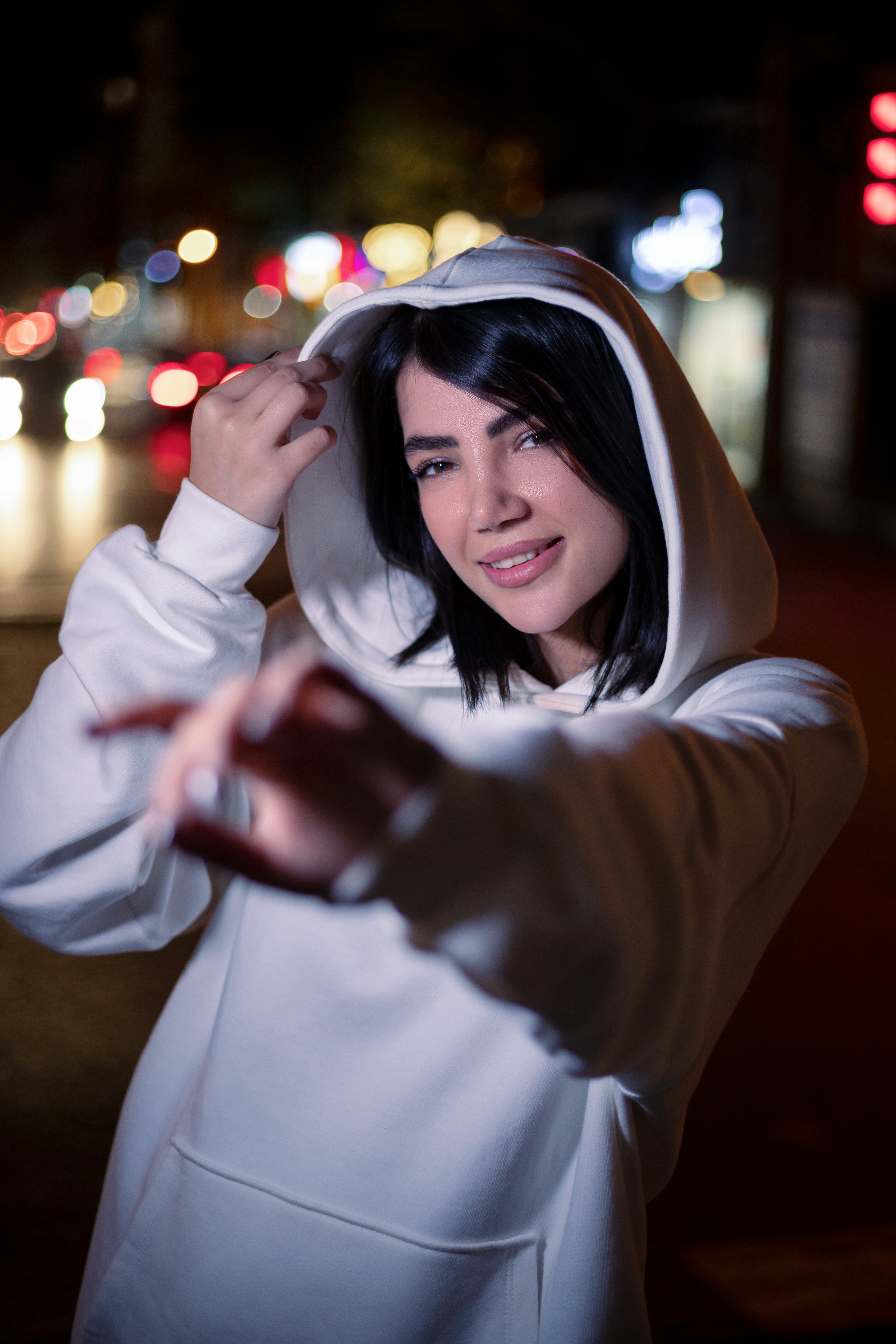 Seorang wanita berhoodie putih berpose untuk berfoto