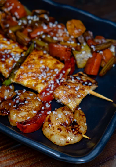 A black plate topped with meat and veggies