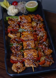 A black plate topped with chicken and veggies