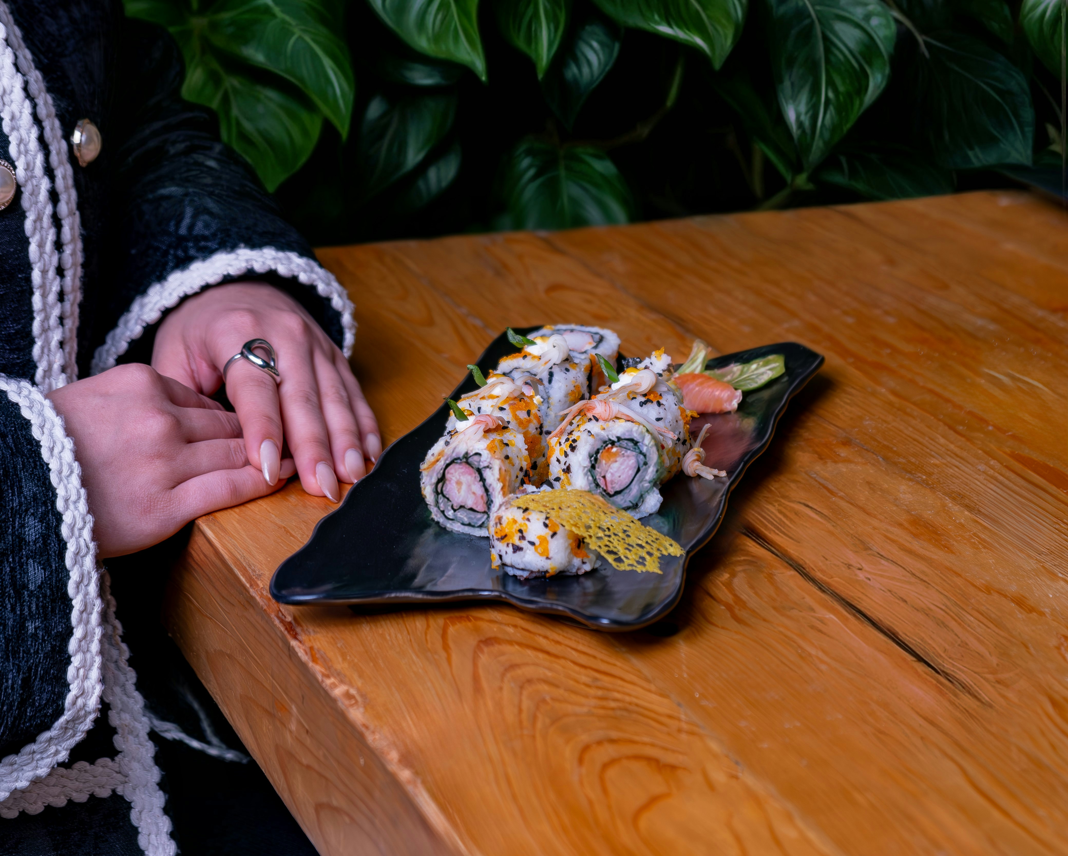 Una persona sentada en una mesa con un plato de sushi