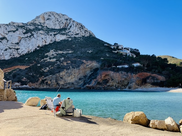 Two people sitting on a bench near a body of water
