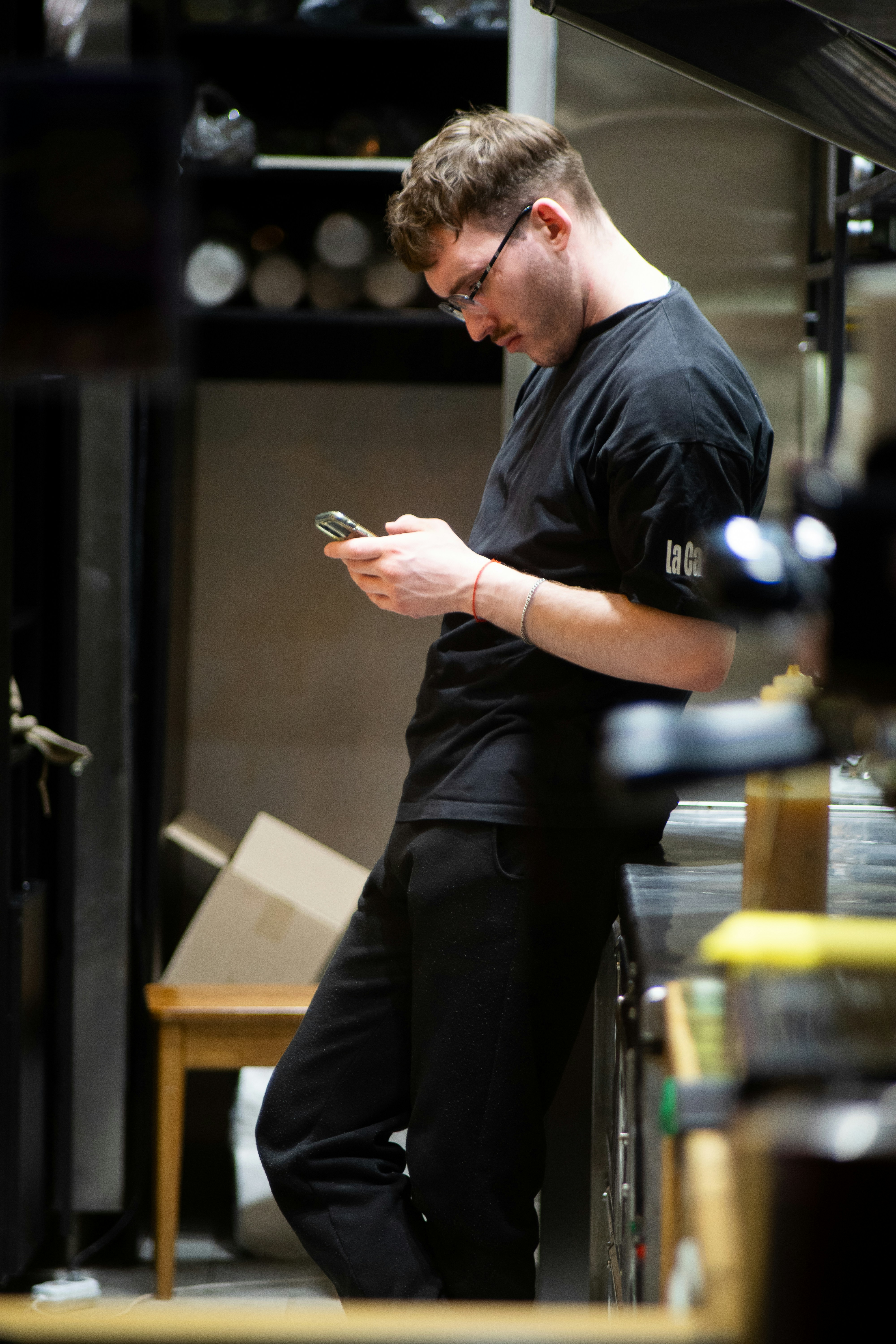 A man standing in a kitchen looking at his cell phone