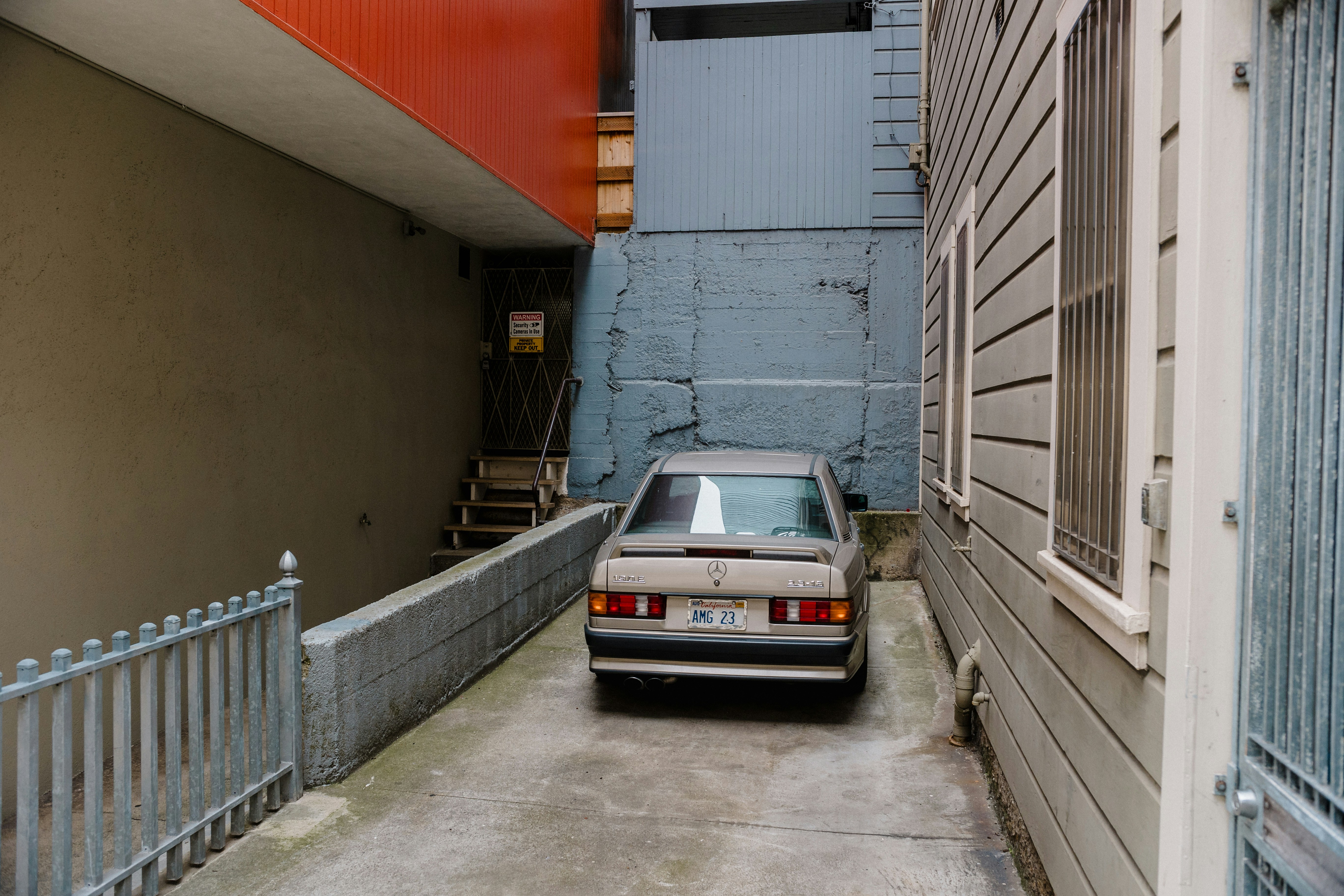 A car is parked in a narrow alley