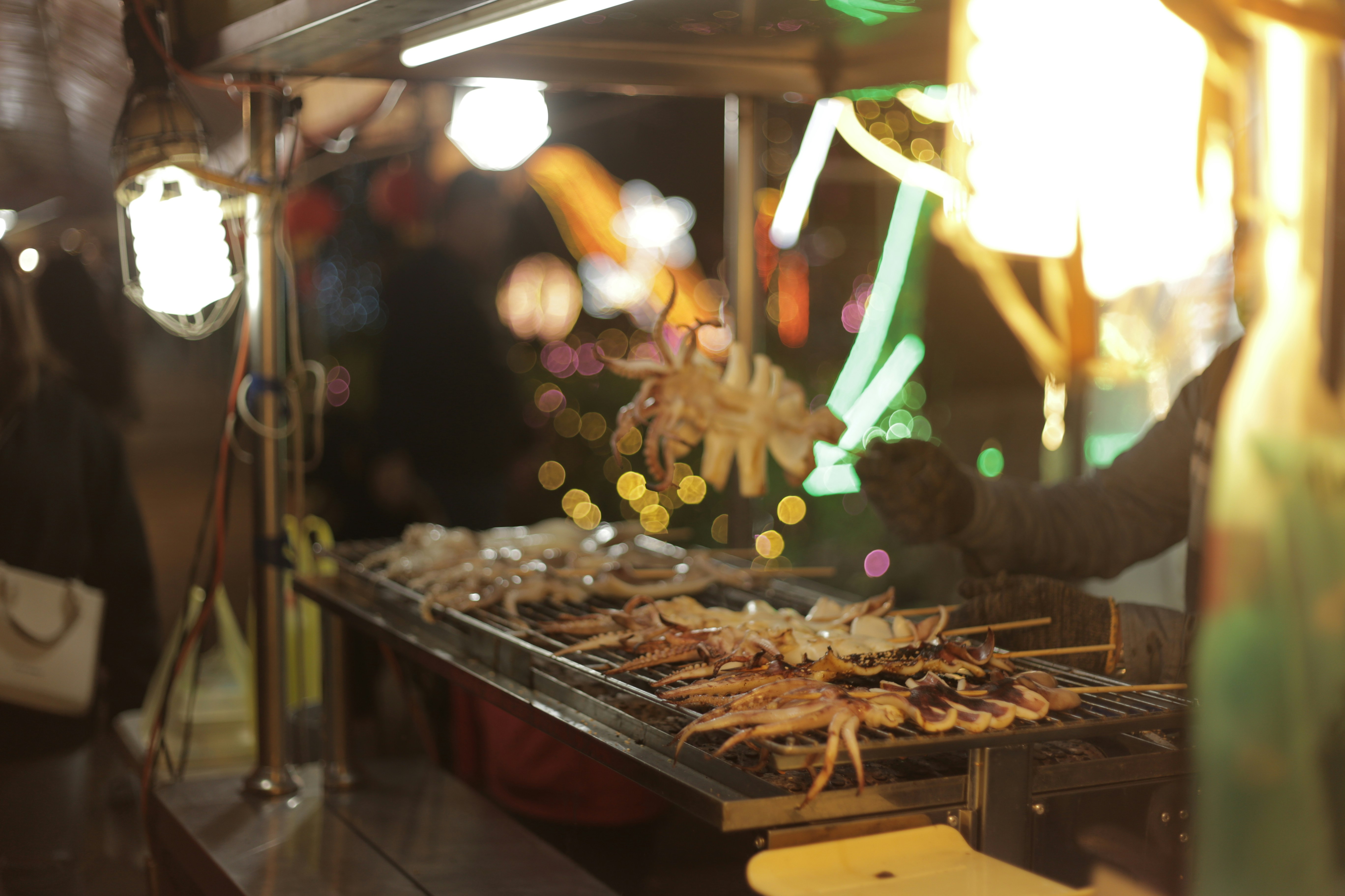 A woman standing in front of a grill with food on it