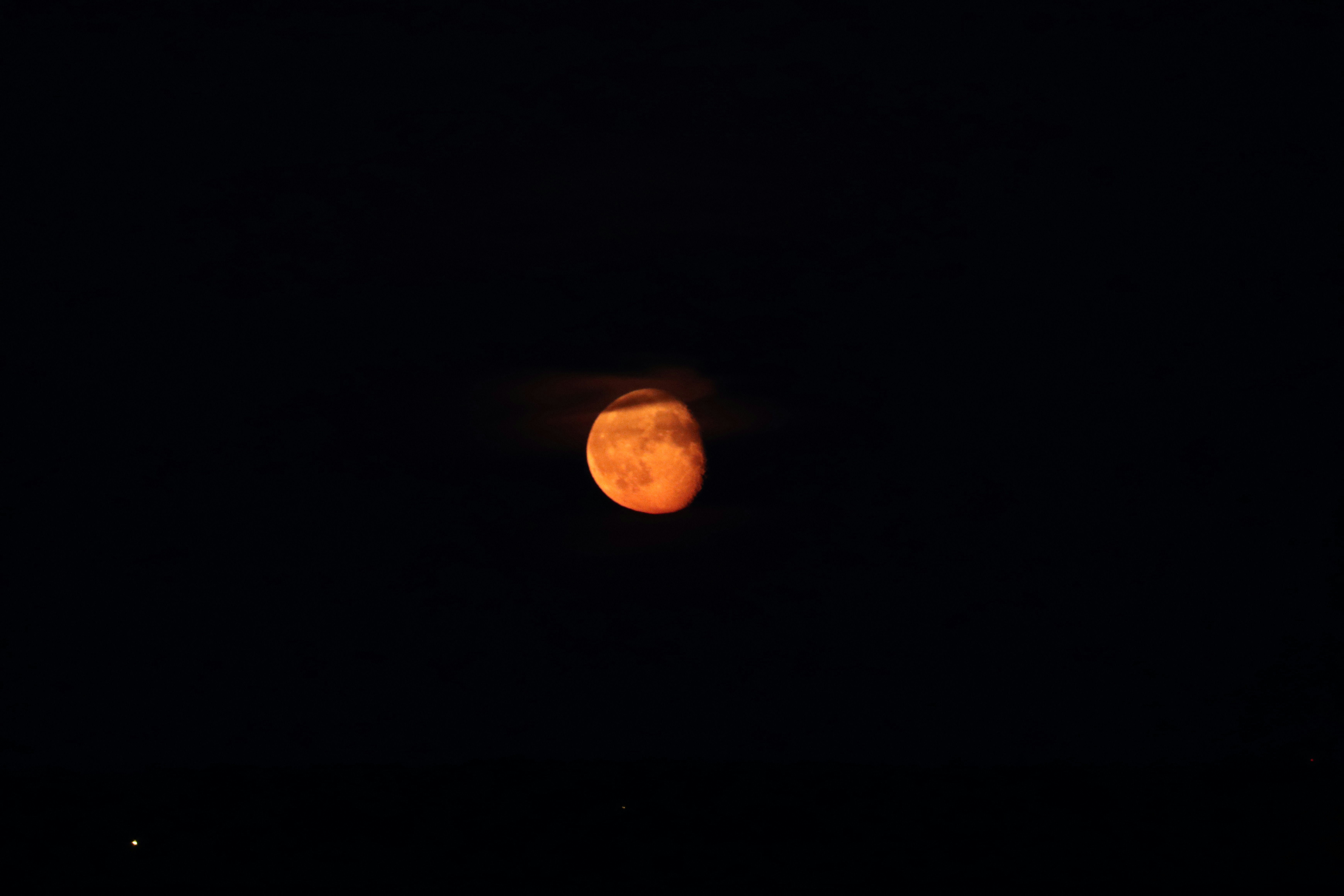 A full moon is seen in the dark sky