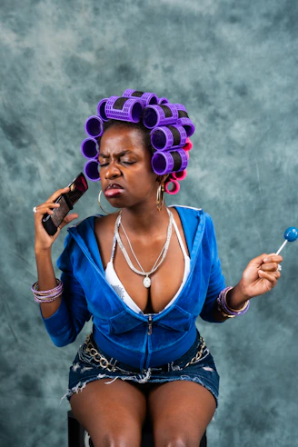 A woman in a chair with a purple hair curl on her head